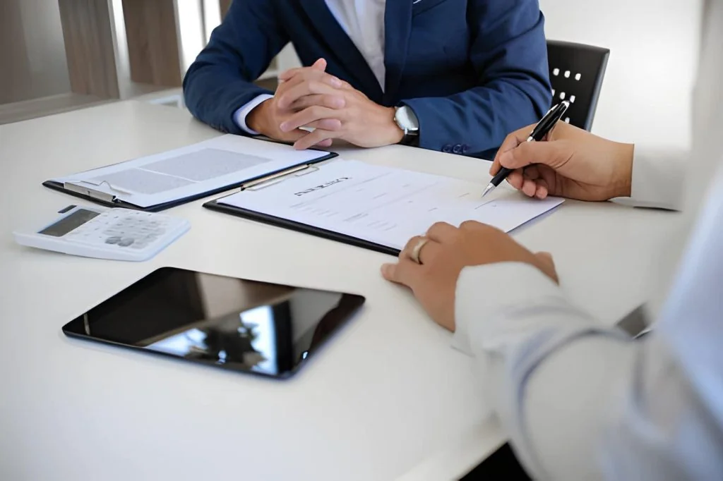 Home insurance adjuster near me—business meeting with documents, calculator, and clipboard.